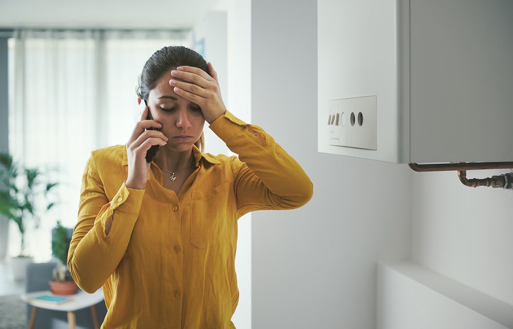 A woman looking frustrated at a broken boiler